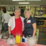 Ivey Lambert Sewell & Kay Laing Menendez serving juice & cinnamon buns in Media Center